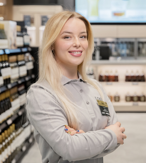 A female employee standing in an LCBO retail store with a big smile.