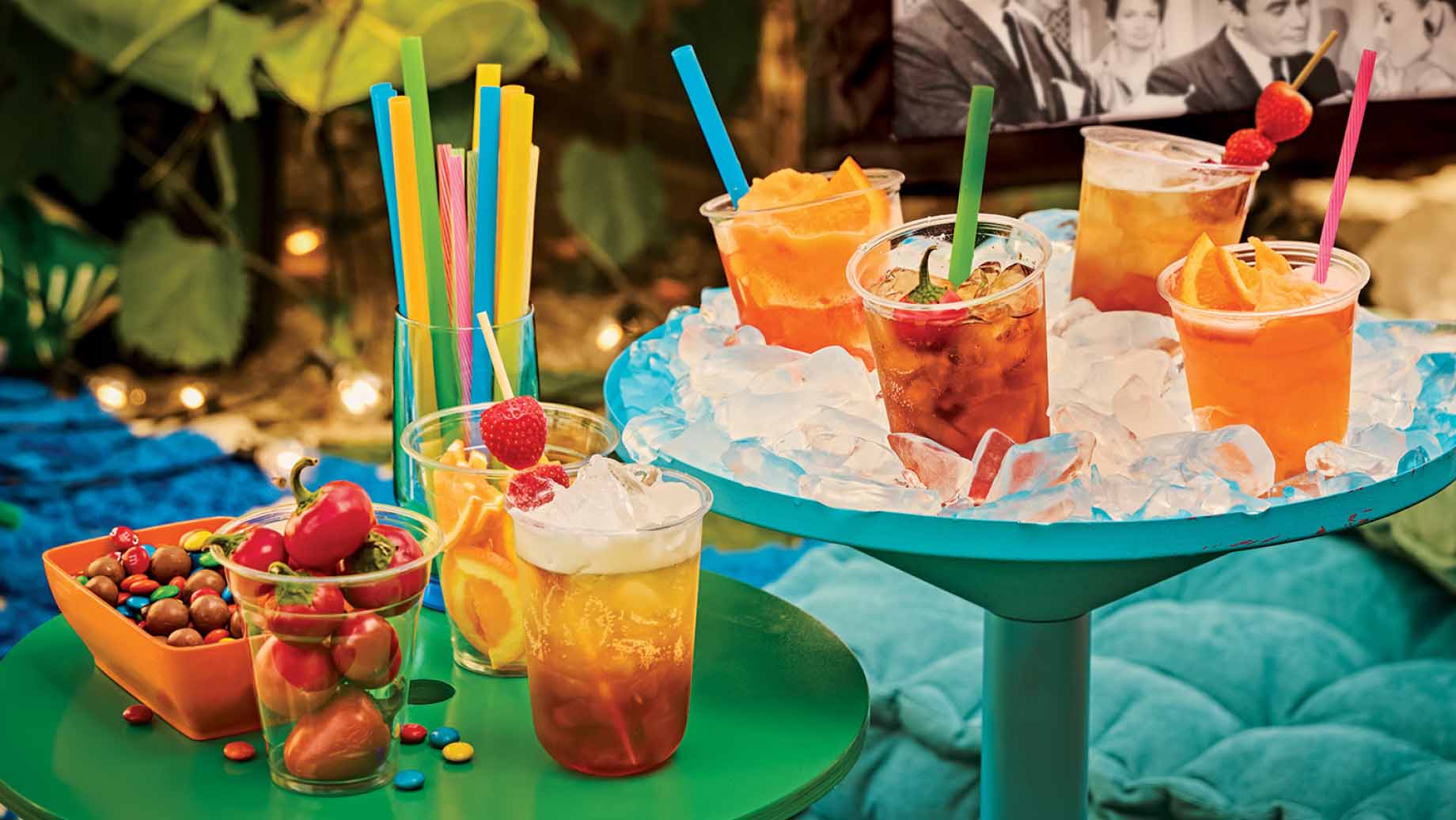 A selection of soda pop cocktails on ice with a movie showing in the background